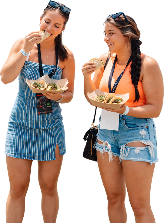Two festivalgoers eating tacos on the lawn at Vinoy Park